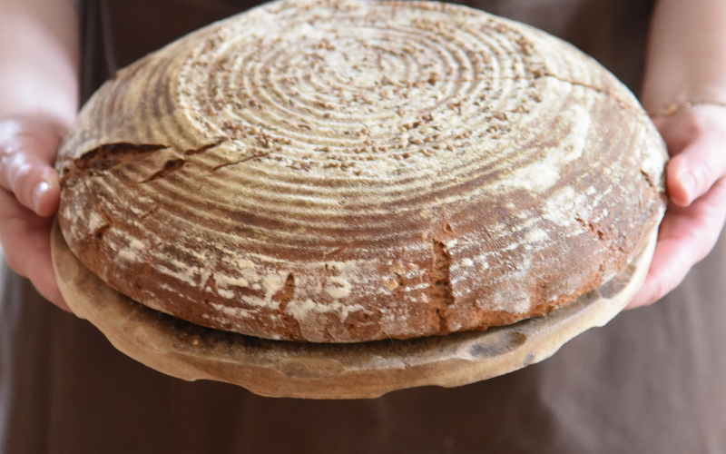 Ein rundes Sauerteigbrot wird auf einem Holzbrett serviert