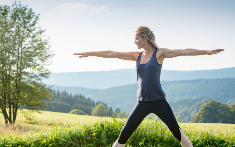 Eine Frau macht auf einer Wiese Yoga