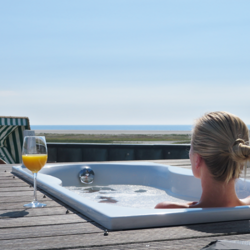 Frau badet auf Außenterrasse im Whirlpool mit Blick auf das Meer