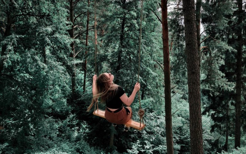 Frau sitzt auf einer Schaukel im Wald