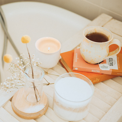 Badewanne mit Blumen, Kaffee, Tee und Büchern auf der Ablage
