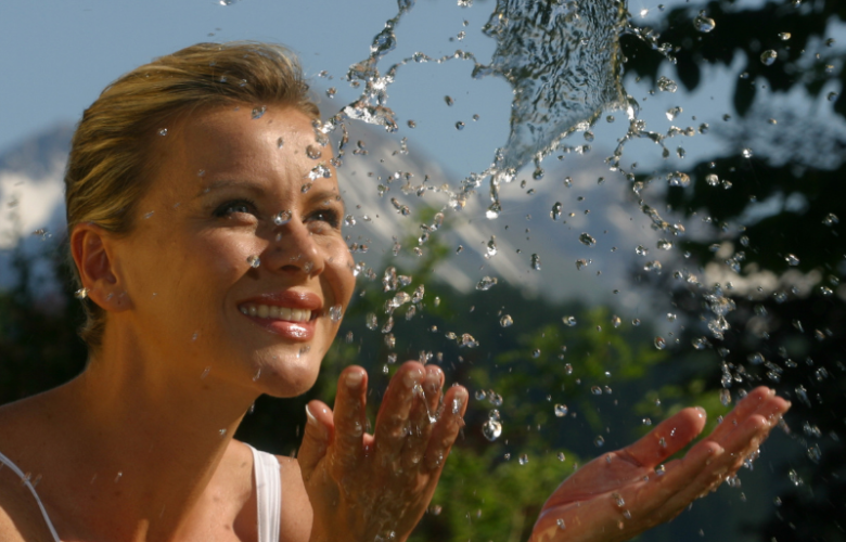 Frau erfrischt sich mit Wasser